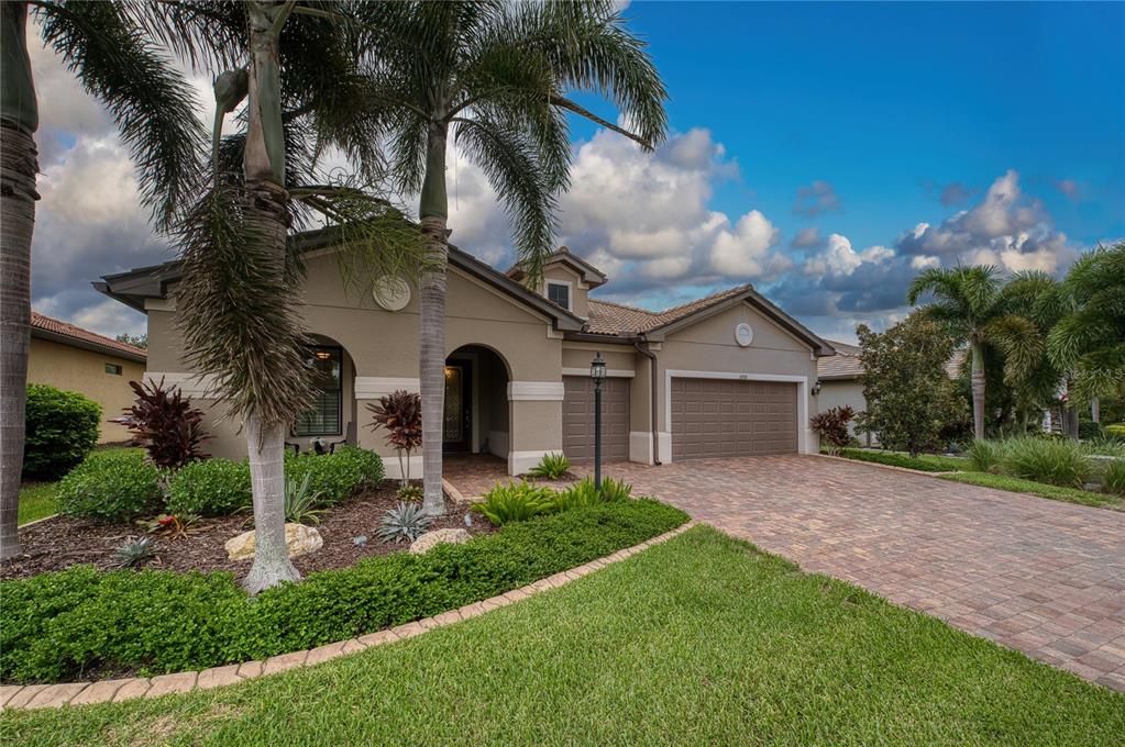A single-story house with a paved driveway, a two-car garage, and palm trees in front — 16918 LOUDON PLACE, BRADENTON, FL