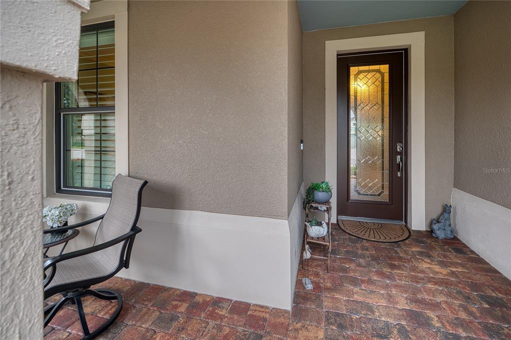 A covered front porch features a brown door with a glass insert and brick pavers — 16918 LOUDON PLACE, BRADENTON, FL