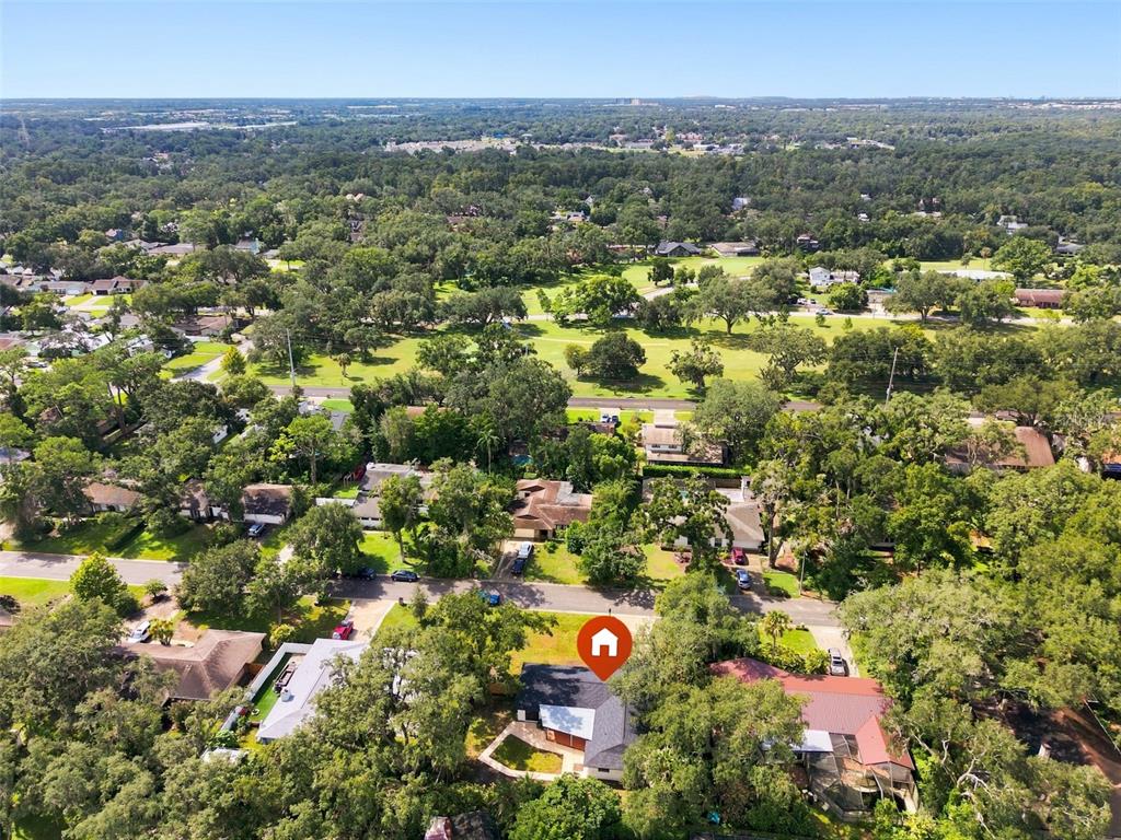 An aerial view shows a residential house with a dark roof surrounded by dense trees — 6622 GLENCOE DRIVE, TEMPLE TERRACE, FL