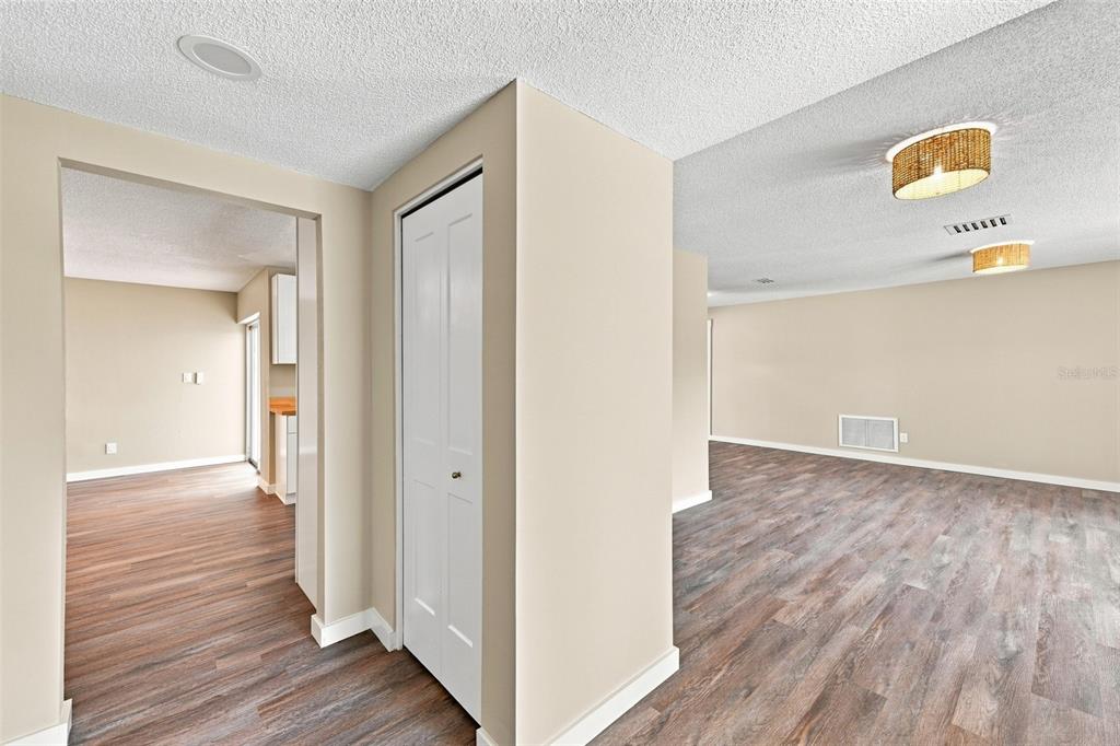 A view of a living area and hallway with wood-look flooring and beige walls — 6622 GLENCOE DRIVE, TEMPLE TERRACE, FL