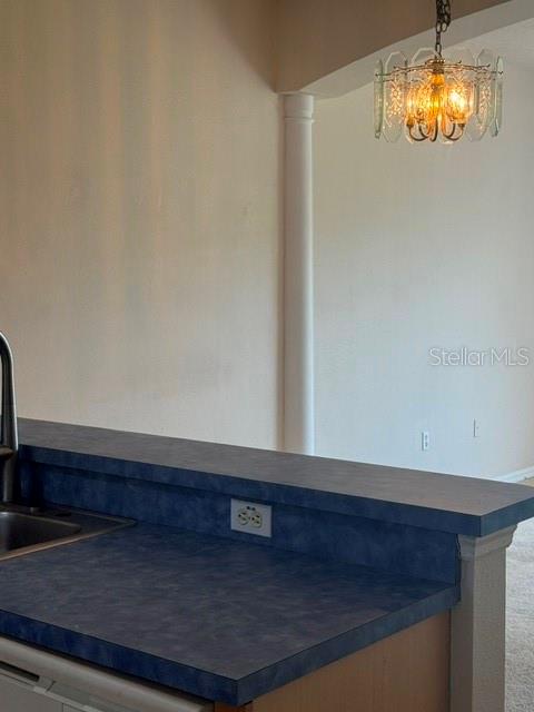 A kitchen counter with a blue laminate surface and a decorative chandelier in the background — 418 MONROE CIRCLE, DAVENPORT, FL