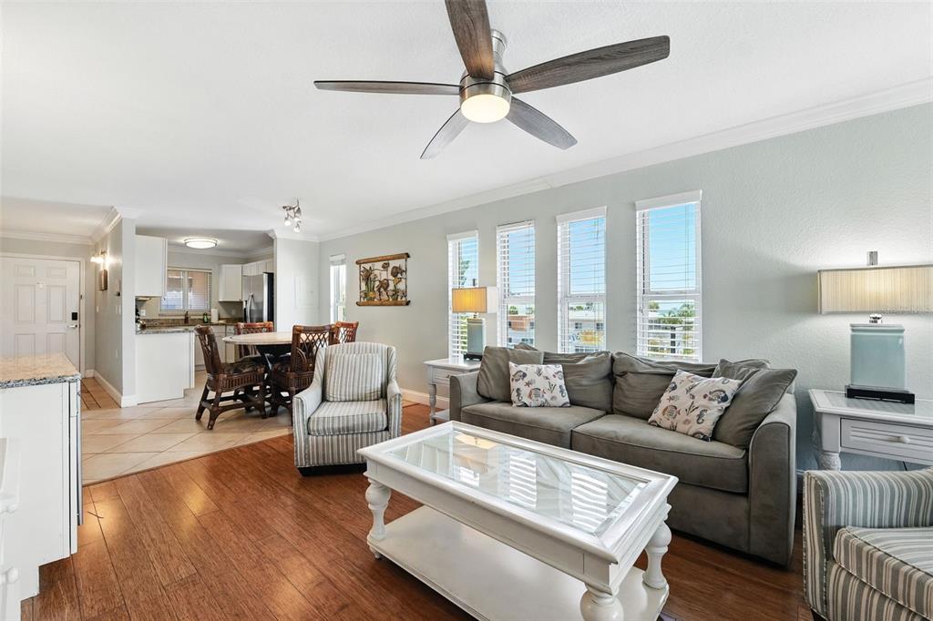 A living room with hardwood floors, a gray sofa, and an open kitchen area — 10265 GULF BOULEVARD UNIT A-301, ST PETERSBURG, FL