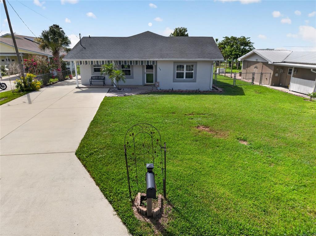 A single-story house with a gray exterior, a concrete driveway, and a front lawn — 148 N LAKE REEDY BOULEVARD, FROSTPROOF, FL