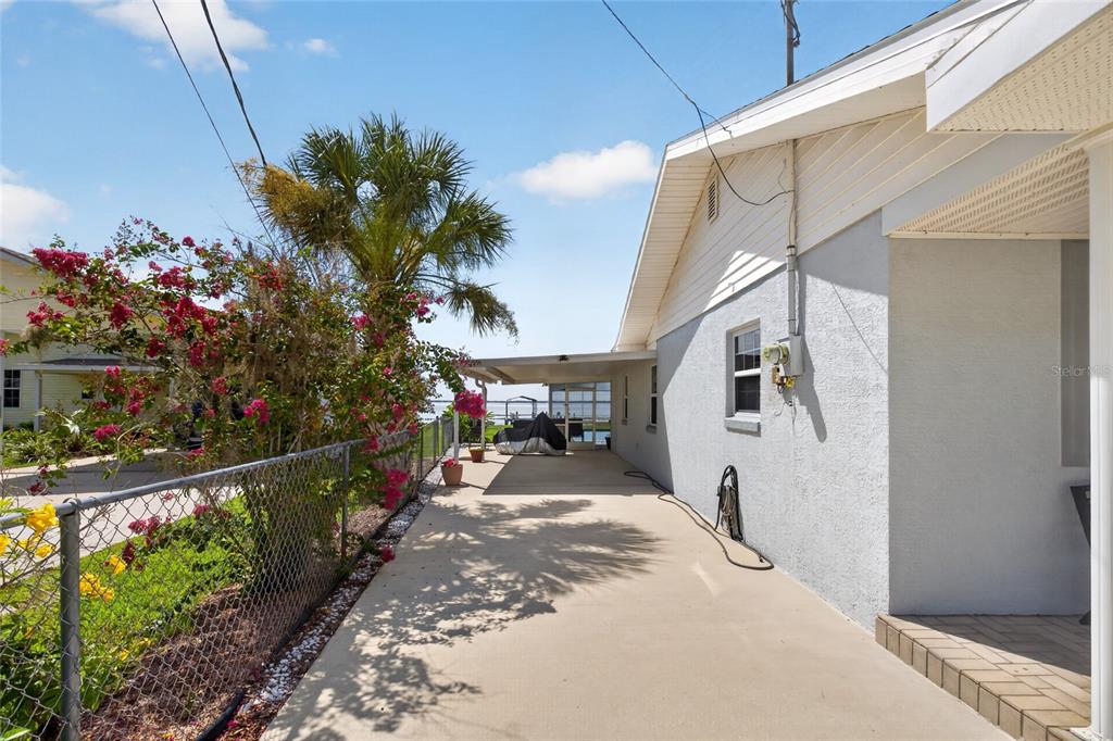 A concrete patio runs along the side of a house next to a chain-link fence — 148 N LAKE REEDY BOULEVARD, FROSTPROOF, FL