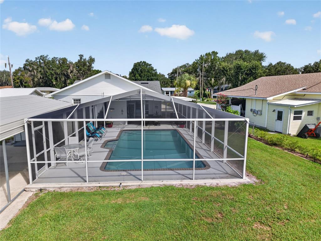 An elevated view of a backyard swimming pool enclosed by a white screen cage — 148 N LAKE REEDY BOULEVARD, FROSTPROOF, FL