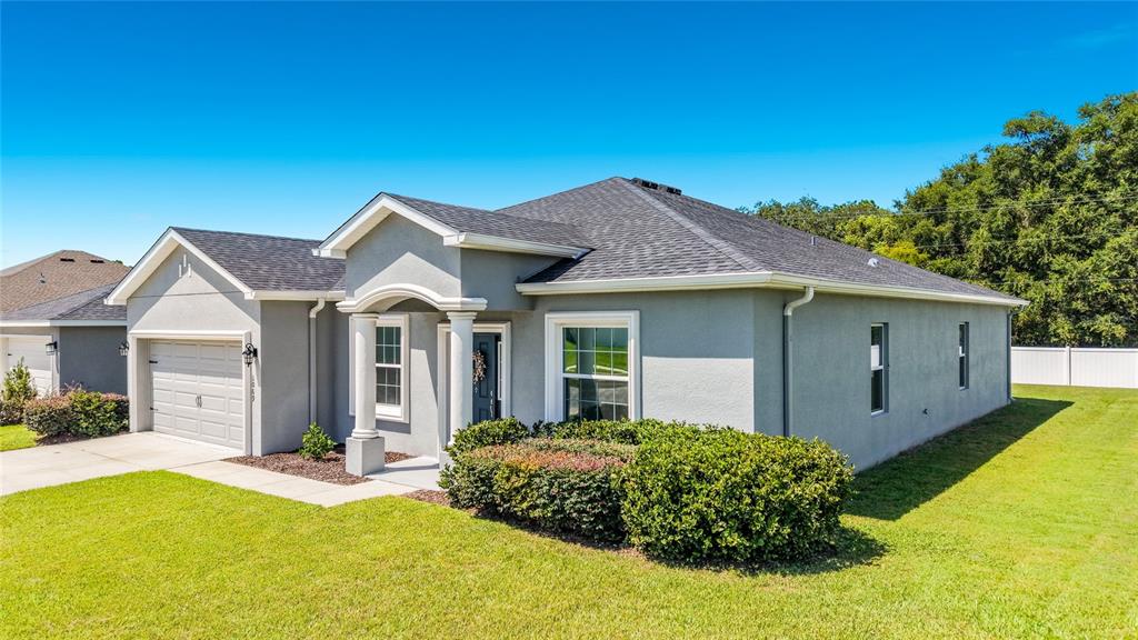 A single-story gray house with a two-car garage, arched entryway, and manicured landscaping — 1069 SANDPIPER LOOP, WINTER HAVEN, FL