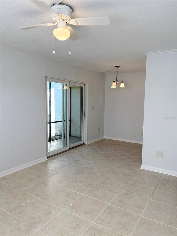 A bedroom with light gray walls, tile flooring, a ceiling fan, and an open closet — 5521 BAY BOULEVARD UNIT 101, PORT RICHEY, FL
