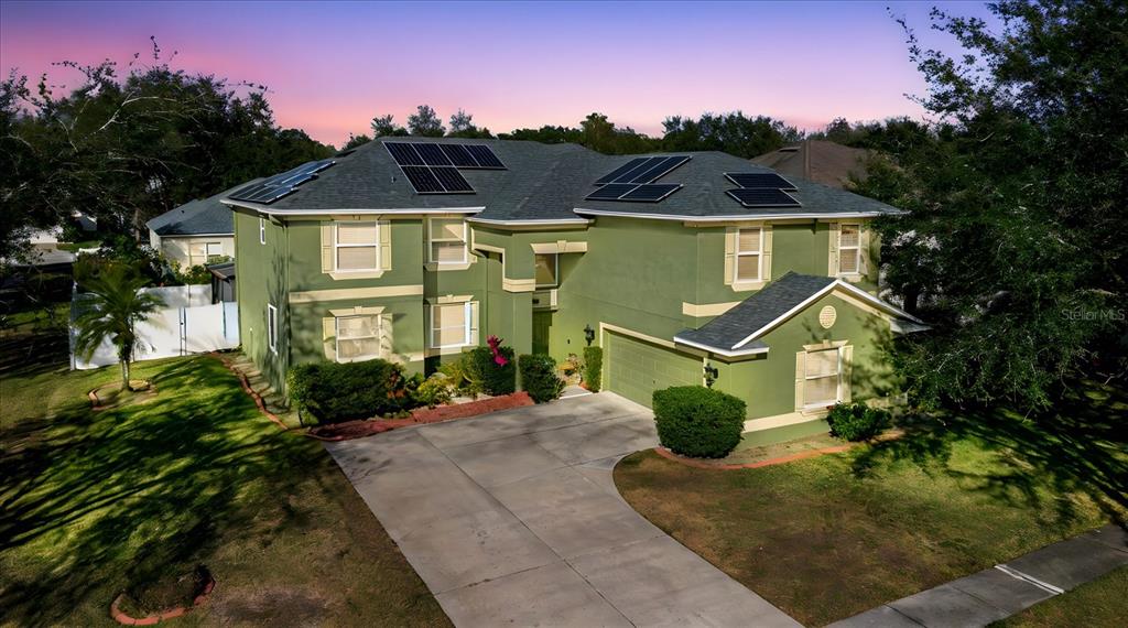 An aerial view of a two-story green house with solar panels on the roof — 2717 AVON RIVER DRIVE, VALRICO, FL