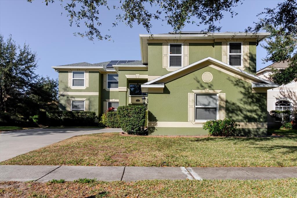 A two-story green house with a concrete driveway and solar panels on the roof — 2717 AVON RIVER DRIVE, VALRICO, FL