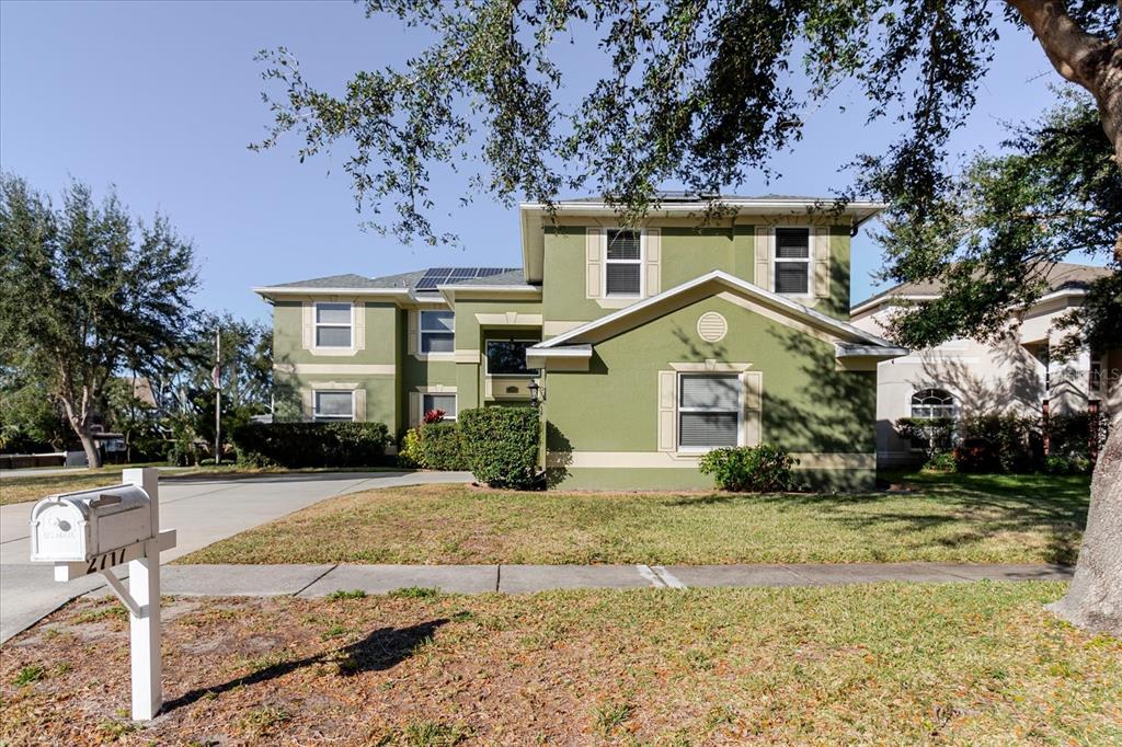 A two-story green house with a white mailbox and solar panels on the roof — 2717 AVON RIVER DRIVE, VALRICO, FL