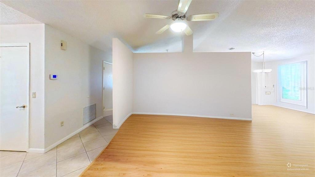 An empty living area features light wood-look flooring, a ceiling fan, and white walls — 1410 NEW ABBEY AVENUE, LEESBURG, FL