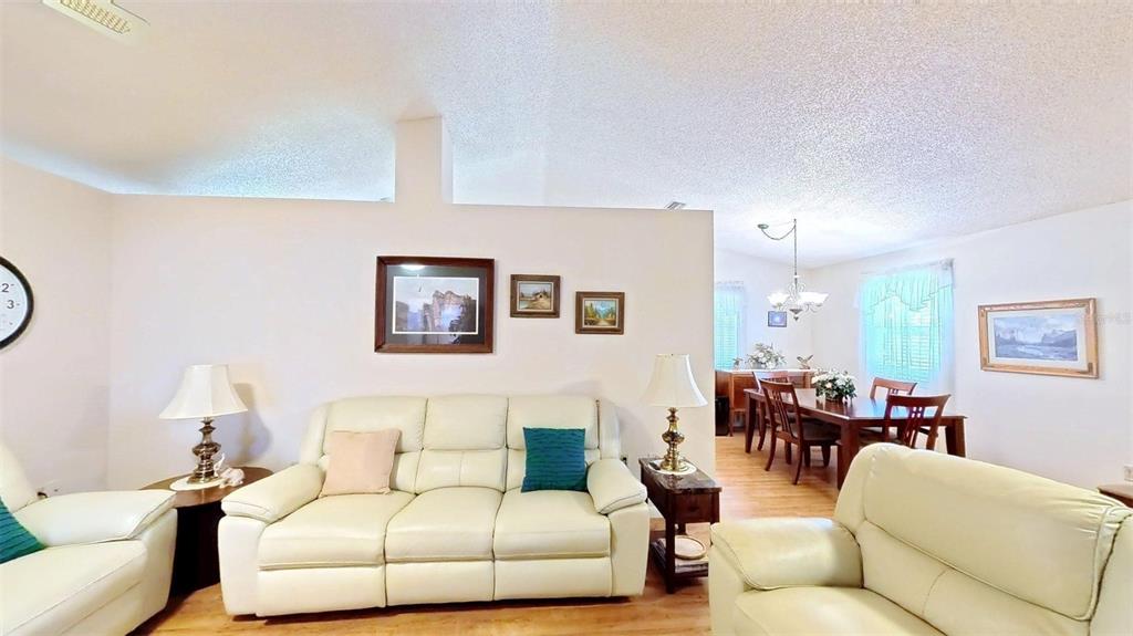A living room with a white sofa and dining area visible in the background — 1410 NEW ABBEY AVENUE, LEESBURG, FL