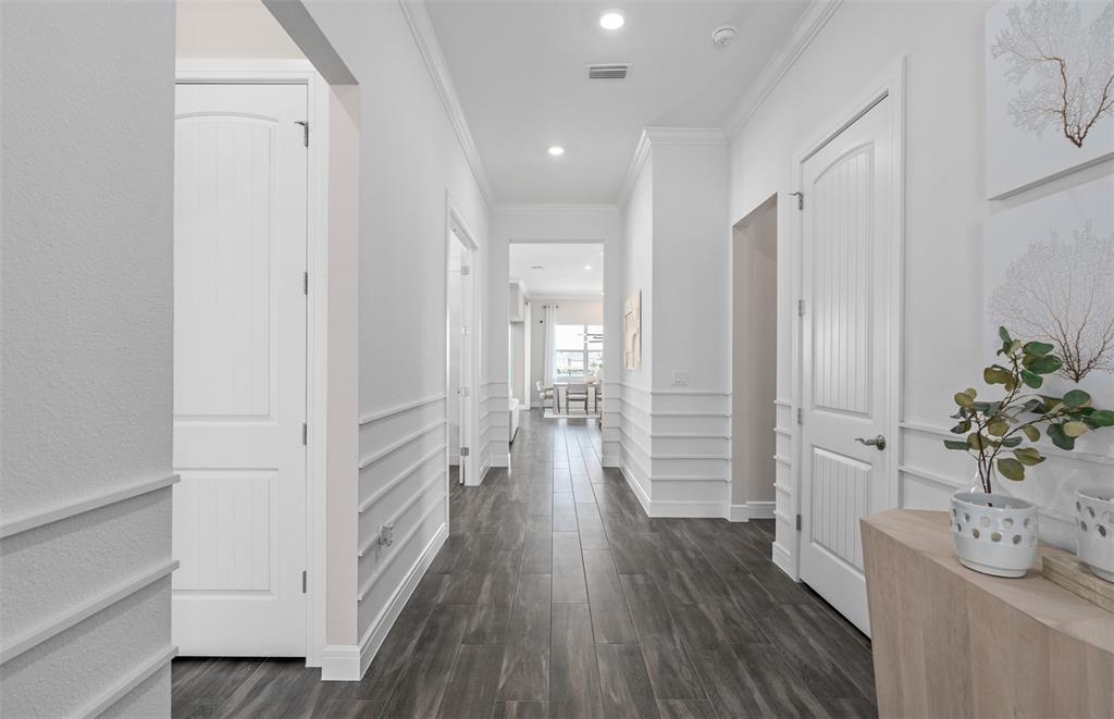 A white hallway with wainscoting, dark wood-look tile flooring, and several closed interior doors — 15000 CANOPY COVER DRIVE, WINTER GARDEN, FL