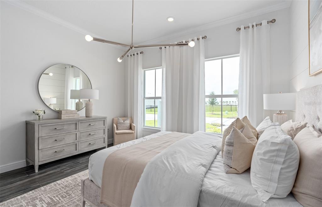 A bright bedroom features a light wood dresser, a round mirror, and a modern chandelier — 15000 CANOPY COVER DRIVE, WINTER GARDEN, FL