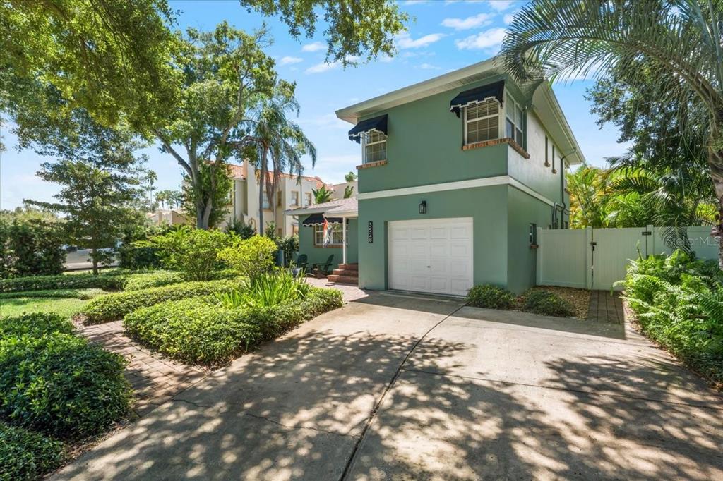 A two-story green house with a white garage door and a paved driveway — 3528 FOSTER HILL DRIVE N, ST PETERSBURG, FL