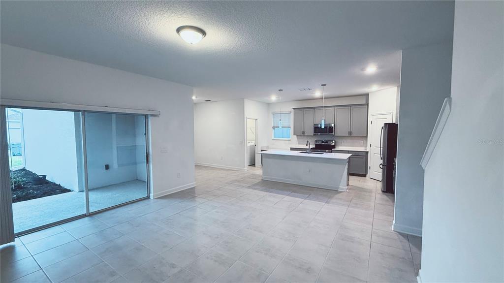 An open-concept kitchen with a central island and sliding glass doors leading to a patio — 11830 LANGUAGE WAY, ORLANDO, FL