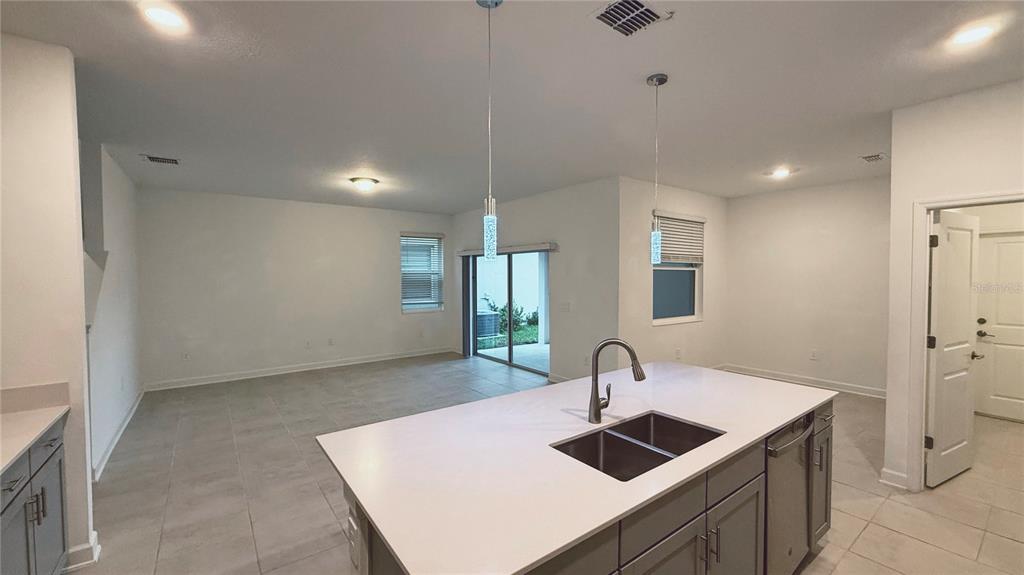 A kitchen island with a double sink sits in an open-concept room with tile flooring — 11830 LANGUAGE WAY, ORLANDO, FL