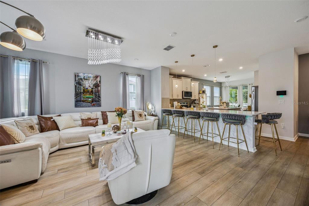 A modern kitchen features white cabinetry, quartz countertops, stainless steel appliances, and wood-look flooring — 11492 SUNSAIL AVENUE, ORLANDO, FL