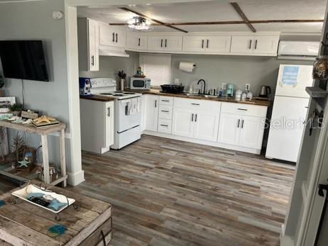 A living room features a grey futon, a wooden crate coffee table, and wood-look flooring — 3803 116TH STREET COURT W, BRADENTON, FL