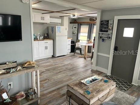 A kitchen with white cabinets, wood-look flooring, and a white refrigerator in an open space — 3803 116TH STREET COURT W, BRADENTON, FL