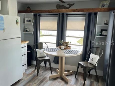 An open-concept living area features a kitchen with white cabinets, a refrigerator, and wood-look flooring — 3803 116TH STREET COURT W, BRADENTON, FL