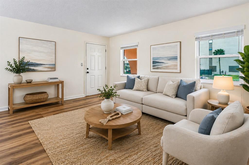 A living room features a beige sofa, a round coffee table, and light wood flooring — 7001 PLACE DE LA PAIX UNIT 2A, SOUTH PASADENA, FL