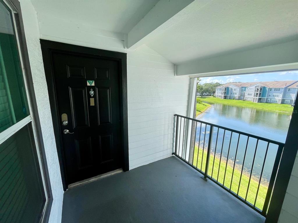 A covered balcony features a black door and a metal railing overlooking a pond — 4103 TROPICAL ISLE BOULEVARD UNIT 138, KISSIMMEE, FL