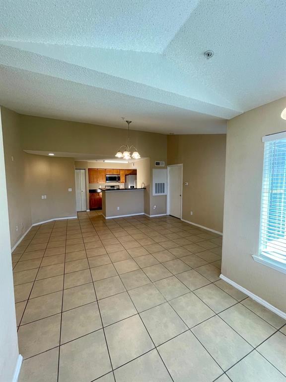 An open-concept living area features tan tile flooring, a vaulted ceiling, and a kitchen with cabinets — 4103 TROPICAL ISLE BOULEVARD UNIT 138, KISSIMMEE, FL