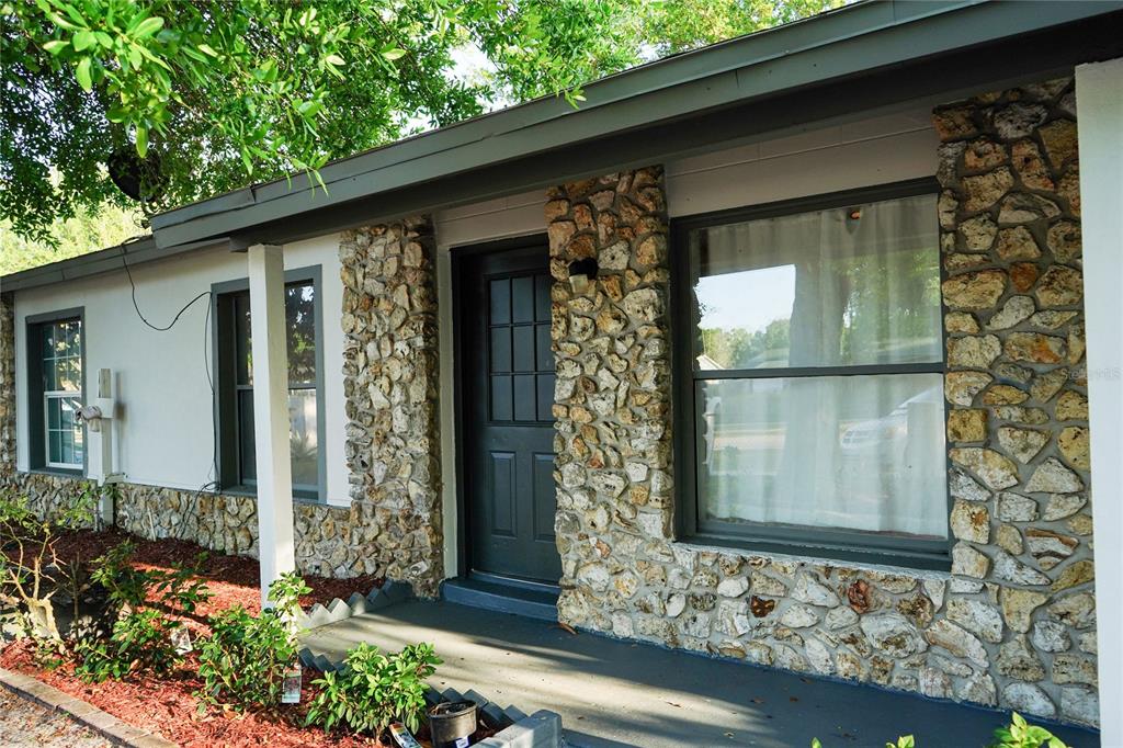 The exterior of a house features a stone facade, a dark front door, and windows — 473 WURST RD, OCOEE, FL