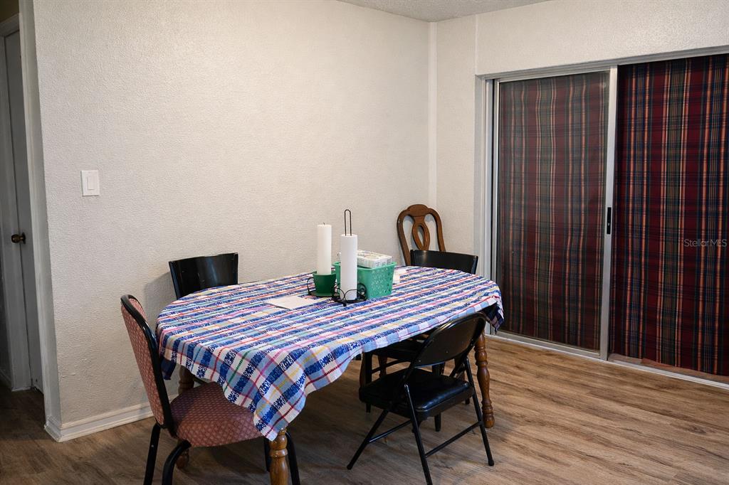 A dining area features a table with a plaid tablecloth, four chairs, and sliding glass doors — 473 WURST RD, OCOEE, FL