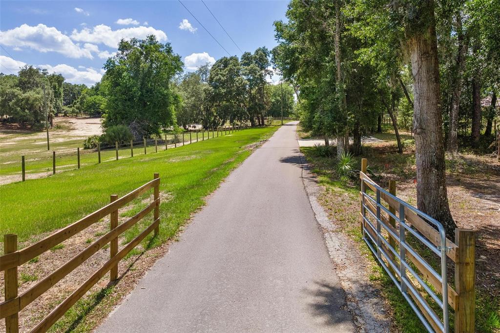 A paved driveway leads past a wooden fence and a metal gate into a wooded area — SE 152ND - (RAVENSWOOD RD) PARCEL B & C, LOTS 16, 17 PLACE, ALTOONA, FL