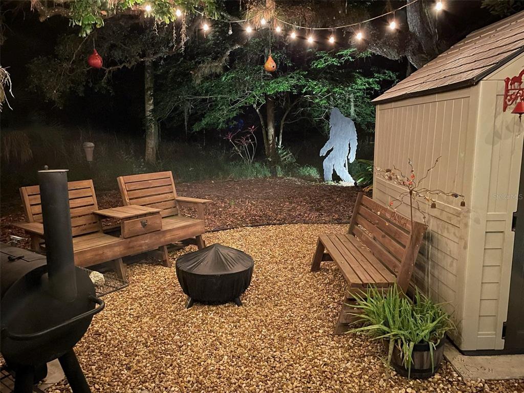An outdoor patio area features wooden benches, a fire pit, and a Bigfoot lawn ornament — 389 LONGHORN DRIVE, RIVER RANCH, FL