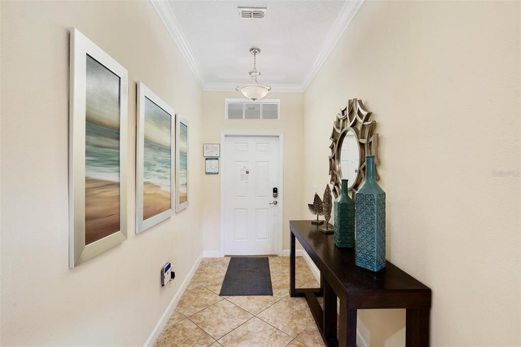 A tiled entryway features a console table, wall art, a mirror, and a white door — 2995 BUCCANEER PALM ROAD, KISSIMMEE, FL