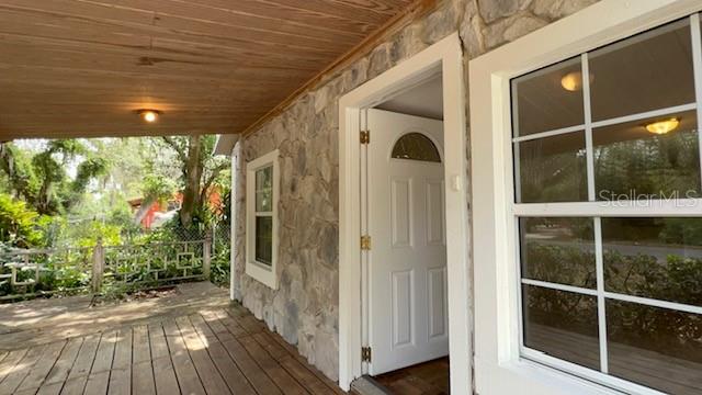A stone-walled house exterior features a wooden porch, a white door, and a grid window — 224 10TH AVENUE, OCOEE, FL