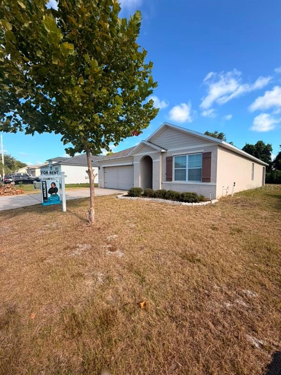 A single-story house with a beige stucco exterior, a two-car garage, and a front lawn — 948 SUMMER GLEN DRIVE, WINTER HAVEN, FL