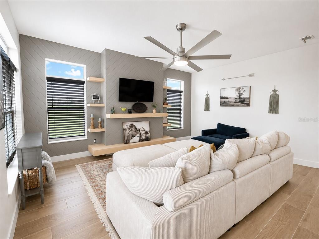 A living room features a chevron-patterned accent wall, a mounted television, and a sectional sofa — 2481 NE FAYE TERRACE, ARCADIA, FL