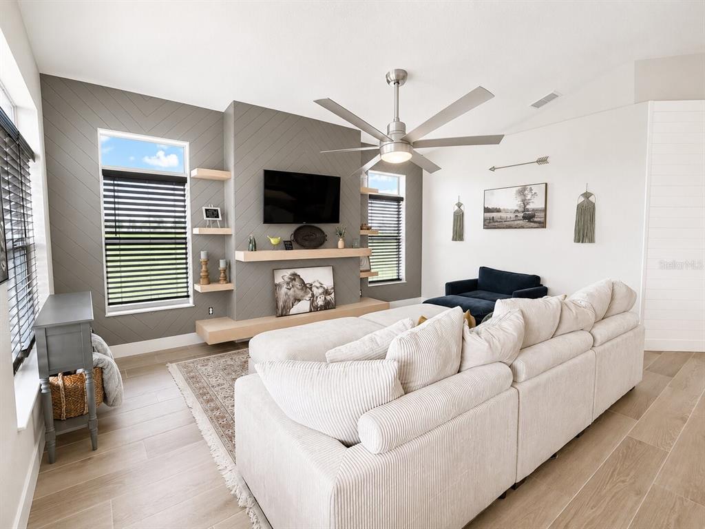 A living room with a dark leather sectional sofa faces a kitchen with bar seating — 2481 NE FAYE TERRACE, ARCADIA, FL