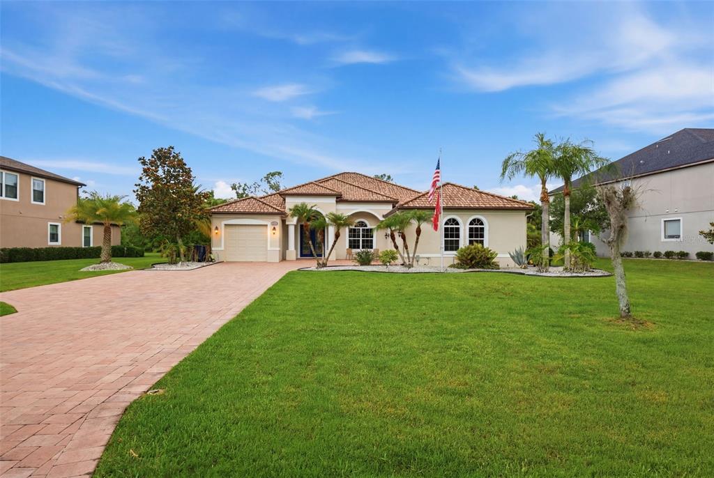 A single-story house with a tile roof, brick driveway, and front lawn under a blue sky — 15809 31ST STREET E, PARRISH, FL