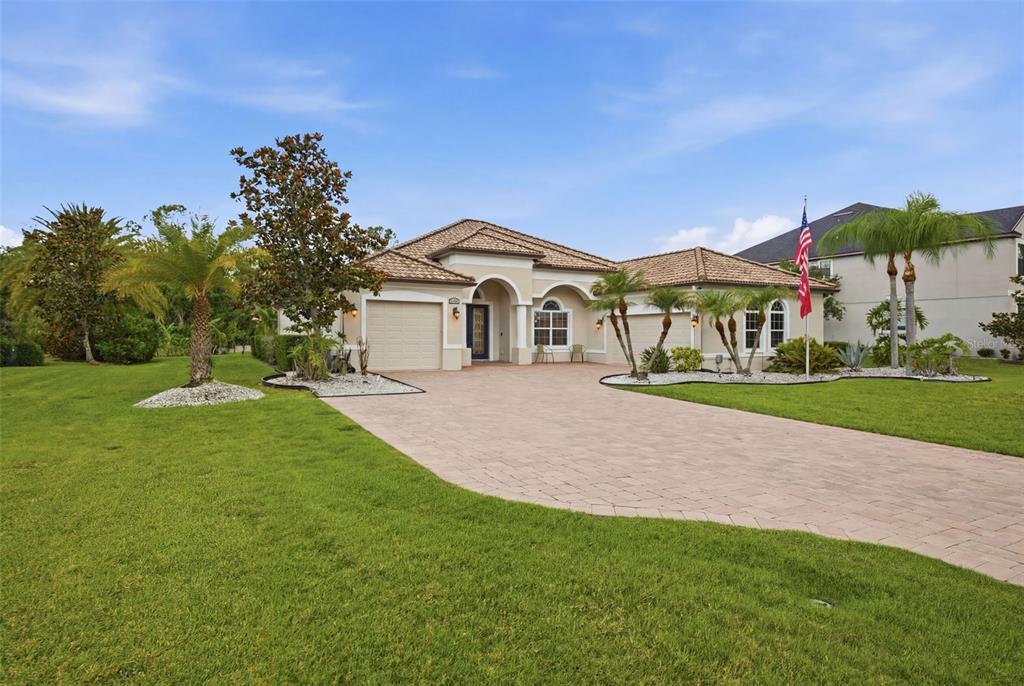 A single-story house with a tiled roof, beige stucco exterior, and a paved driveway — 15809 31ST STREET E, PARRISH, FL