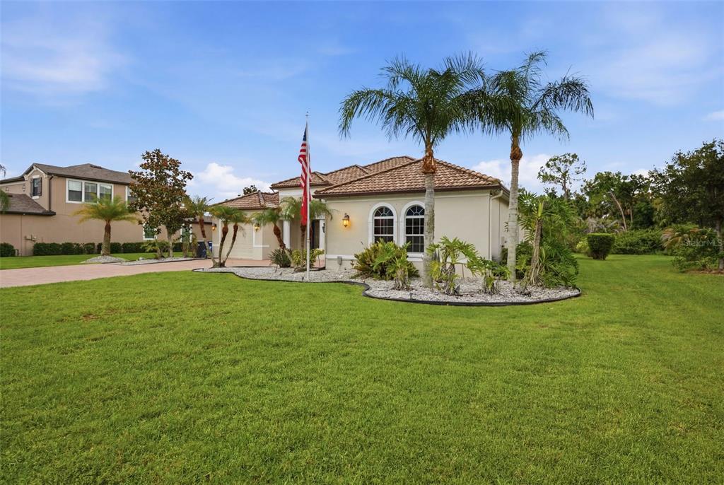A single-story house with a tiled roof, palm trees, and an American flag in front — 15809 31ST STREET E, PARRISH, FL