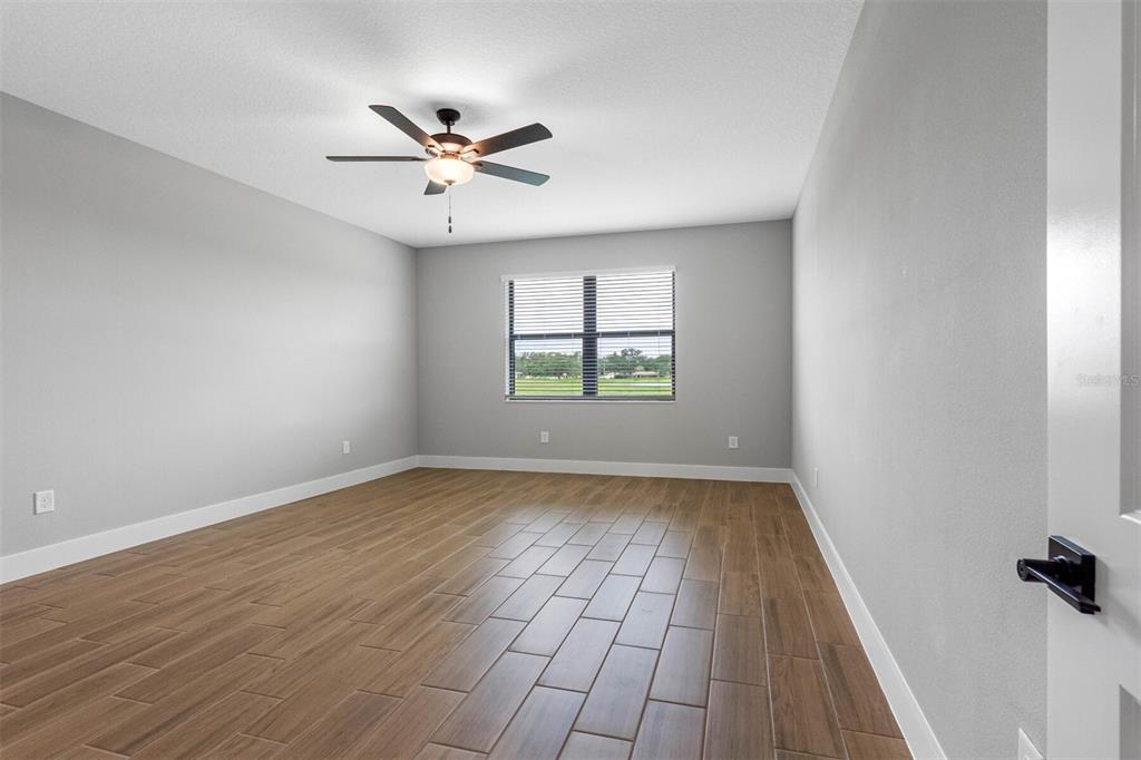 An empty bedroom features light gray walls, wood-look tile flooring, and a ceiling fan — 13439 WALDEN SHEFFIELD ROAD, DOVER, FL