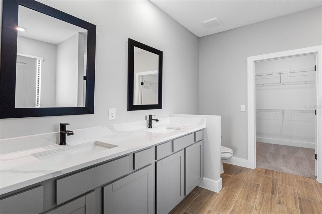 A bathroom features a double vanity with gray cabinets, white countertops, and two black mirrors — 13439 WALDEN SHEFFIELD ROAD, DOVER, FL