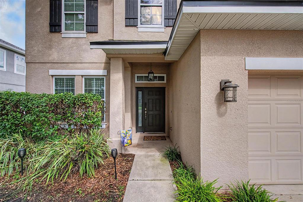 The exterior of a two-story house features a concrete walkway leading to a dark front door — 2622 RED FERN DRIVE, DOVER, FL