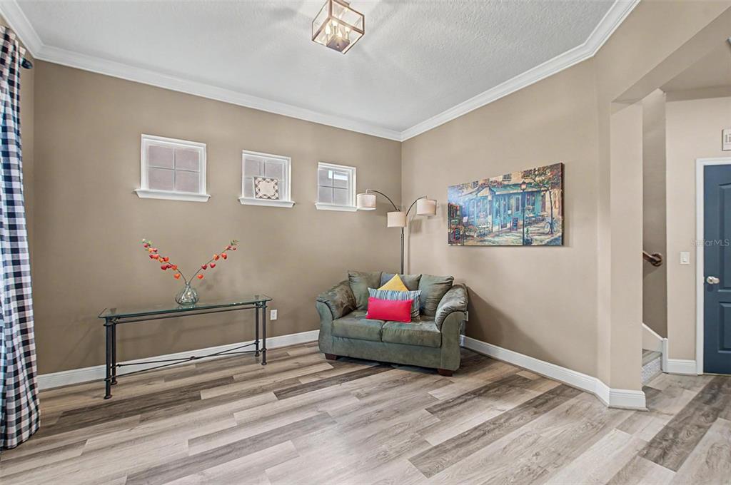 A living area features light brown walls, wood-look flooring, a small sofa, and a glass console — 2622 RED FERN DRIVE, DOVER, FL