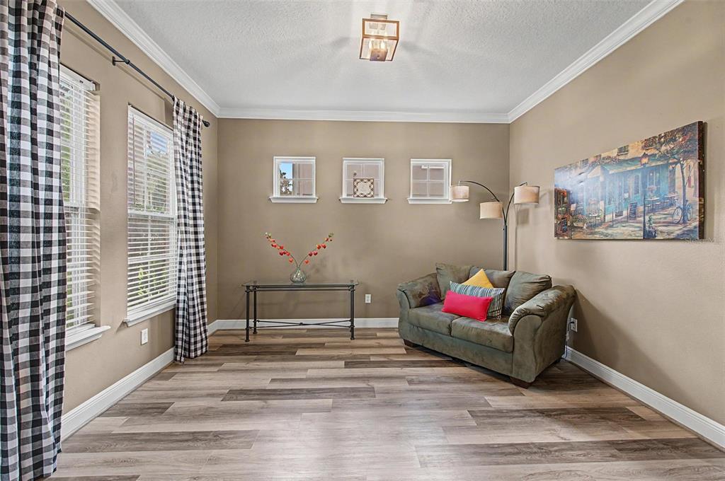 A living room with wood-look flooring, a small sofa, a glass console table, and windows — 2622 RED FERN DRIVE, DOVER, FL