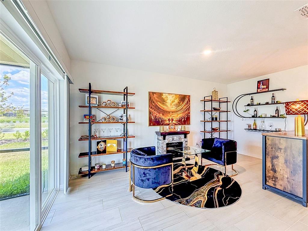 A sitting area features two blue velvet chairs, a fireplace, shelving, and a bar area — 12227 RADIANT GEM TRL, PARRISH, FL