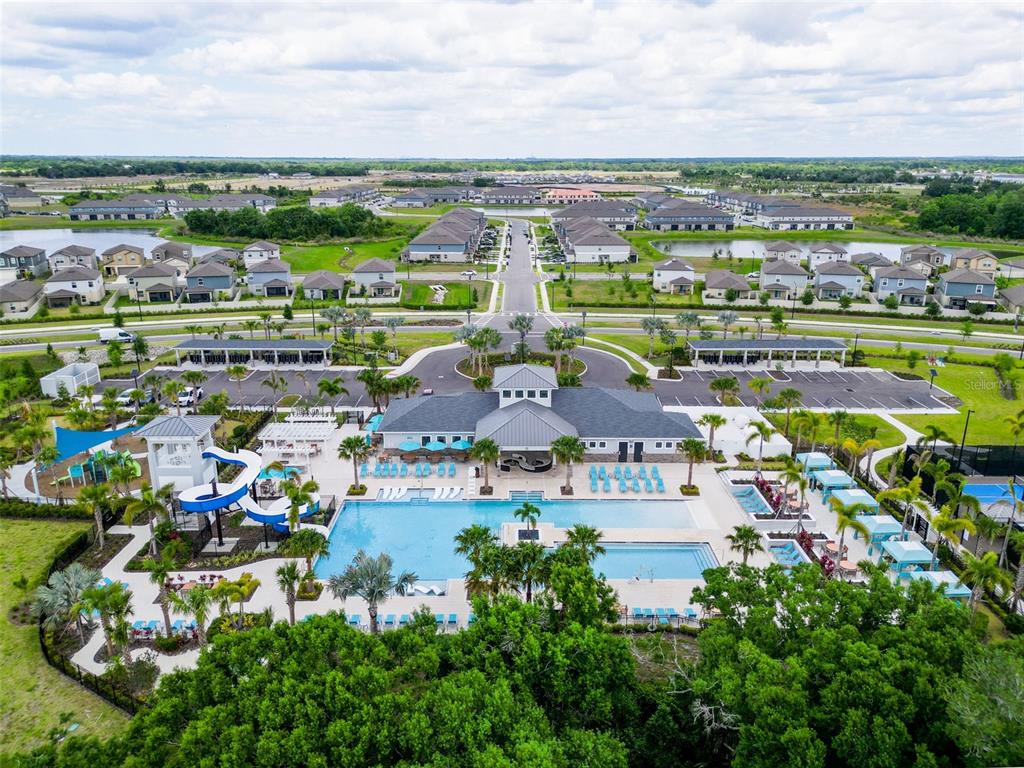 An aerial view shows a community clubhouse with a swimming pool, water slide, and parking — 12227 RADIANT GEM TRL, PARRISH, FL