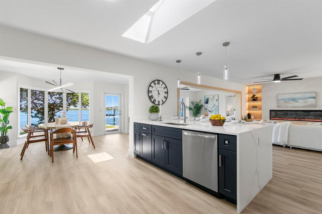 A modern kitchen with a dark blue island overlooks a dining area and waterfront view — 202 DRIFTWOOD LANE, LARGO, FL