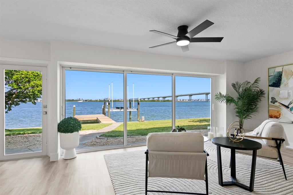 A living room with a ceiling fan, sliding glass doors, and a view of the water — 202 DRIFTWOOD LANE, LARGO, FL