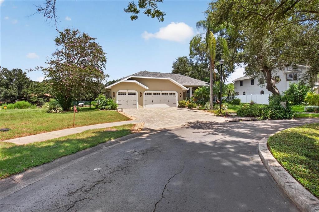 A tan single-story house with a three-car garage and a paved driveway — 8735 CRESCENT FOREST BOULEVARD, NEW PORT RICHEY, FL